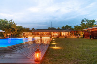 The evening view of the property featuring the swimming pool and rooms in the background