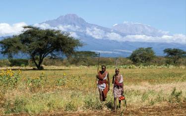 Maasai warriors walking in front of Mt Kilimanjaro