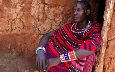 Maasai warrior in front of his hut