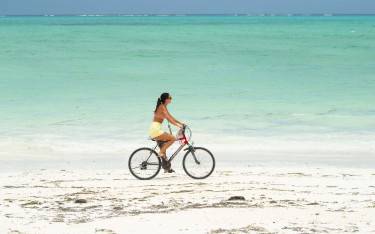 Thumbnail of Woman cycling on the beach
